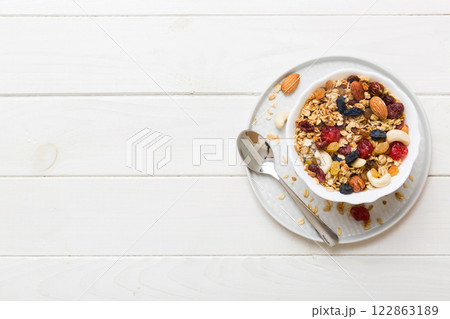 Cooking a wholesome breakfast. Granola with Various dried fruits and nuts in a bowl. The concept of a healthy dessert. Flat lay, top view with copy space Cooking a wholesome breakfast. Granola with Various dried fruits and nuts in a bowl. The concept of a healthy dessert. Flat lay, top view with copy space 122863189