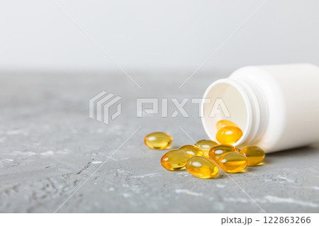 Soft gels pills with Omega-3 oil spilling out of pill bottle close-up. Gel capsules bottle white surface. Omega 3, multivitamins, Calcium, antibiotics. Health. Immunity 122863266