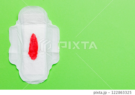 Women hygiene products or Sanitary pad with red feather on colored background. Pastel color. Closeup. Empty place for text. Female daily hygiene Women hygiene products or Sanitary pad with red feather on colored background. Pastel color. Closeup. Empty place for text. Female daily hygiene 122863325