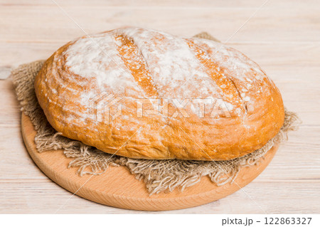 Freshly baked bread on cutting board against white wooden background. perspective view bread with copy space 122863327
