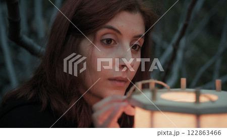 Woman Reflects On The Uncertain Future With A Lantern At Night In Spooky Forest 122863466