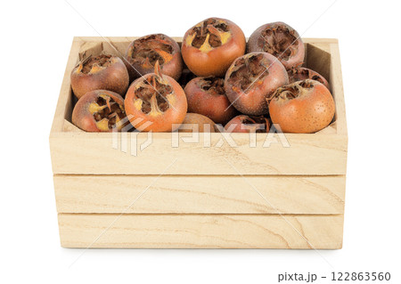 Brown fresh medlars in wooden box isolated on white background. Mespilus germanica close-up 122863560