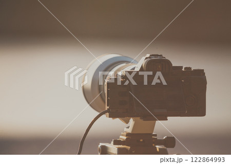 Camera DSLR set on tripod capturing sunset on beach. Camera DSLR set on tripod capturing sunset on beach. 122864993