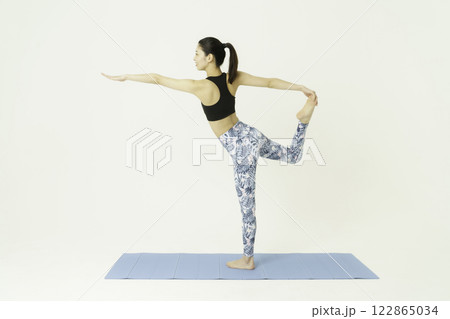 白背景のダンサーポーズをする若い女性　ヨガ 122865034