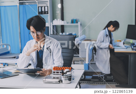 Positive doctor working on laptop in medical office, portrait. Positive doctor working on laptop in medical office, portrait. 122865139