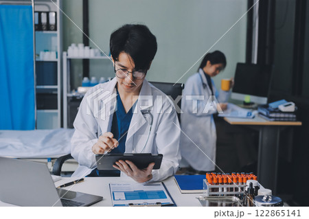 Positive doctor working on laptop in medical office, portrait. Positive doctor working on laptop in medical office, portrait. 122865141