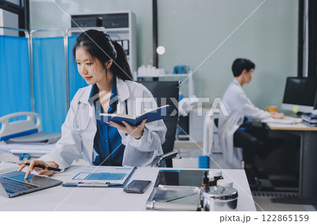 Positive doctor working on laptop in medical office, portrait. Positive doctor working on laptop in medical office, portrait. 122865159