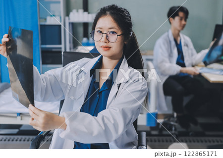 Positive doctor working on laptop in medical office, portrait. 122865171