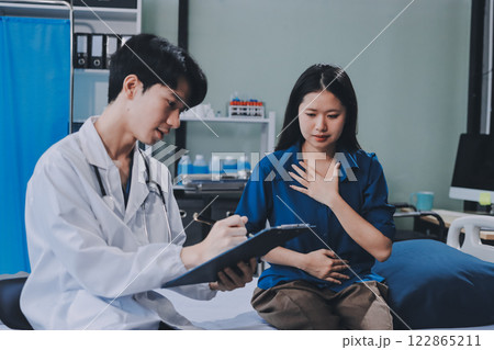 doctor consulting senior old patient filling form at consultation. Professional physician wearing white coat talking to mature woman signing medical paper at appointment visit in clinic. 122865211
