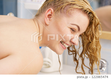 Woman washing hair in bathroom sink 122865474