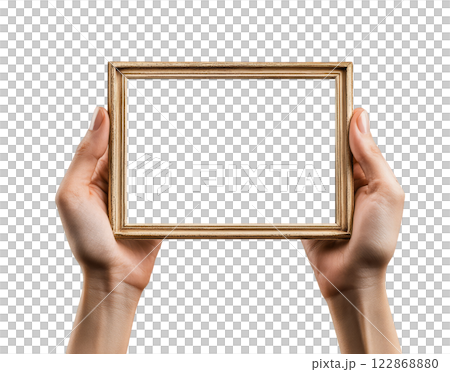 Two hands holding a blank, rectangular, gold picture frame are isolated on a transparent background. 122868880