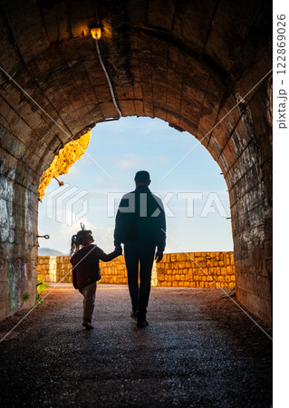 Father and daughter in pedestrian tunnel through a rock or mountain near Petrovac town in winter time, Montenegro 122869026