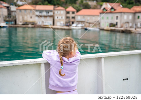 Little girl traveling with family by ferry. Crossing from one bank to another of Kotor bay in Montenegro Little girl traveling with family by ferry. Crossing from one bank to another of Kotor bay in Montenegro 122869028