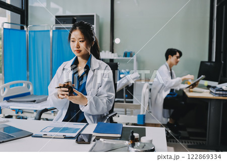 Positive doctor working on laptop in medical office, portrait. Positive doctor working on laptop in medical office, portrait. 122869334
