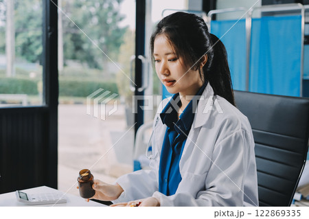 Positive doctor working on laptop in medical office, portrait. Positive doctor working on laptop in medical office, portrait. 122869335