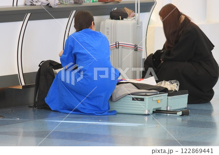 空港の出発ロビーで荷物の詰め替えをする搭乗客 122869441