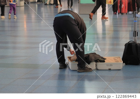空港の出発ロビーで荷物の詰め替えをする搭乗客 122869443