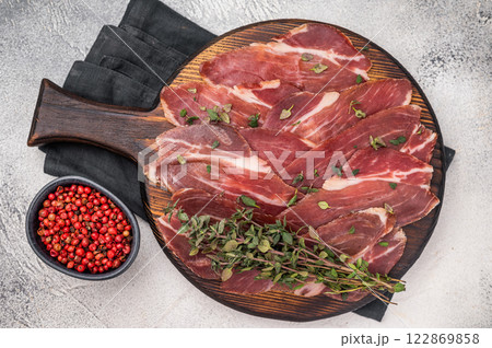 Guanciale dried speck ham, pork cured meat on wooden board. grey background. top view Guanciale dried speck ham, pork cured meat on wooden board. grey background. top view 122869858