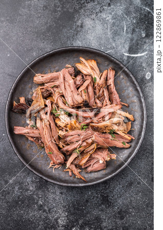 A tantalizing plate of pulled brisket, slow-cooked to perfection, drizzled with barbecue sauce for added flavor. black background. top view A tantalizing plate of pulled brisket, slow-cooked to perfection, drizzled with barbecue sauce for added flavor. black background. top view 122869861