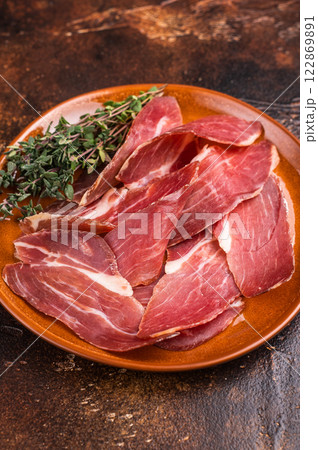 Balkan Prsut prshut, sliced cured pork meat ham on plate. brown background. top view 122869891