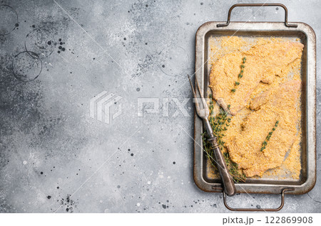 Cooking of Raw breaded Wiener Schnitzel steak in steel tray. gray background. top view 122869908