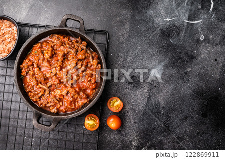 Bolognese sauce with minced beef, tomato paste and herbs in a skillet. black background. top view 122869911