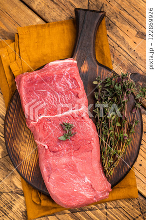Fresh raw bison meat displayed on a wooden board, showcasing its rich red color and tenderness, ideal for gourmet cooking adventures. wooden background. top view 122869926