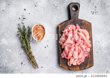 Raw sliced Chicken meat, strips fillets on wooden board. grey background. top view 122869942