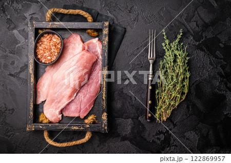 Raw pork chop fillet steaks in a wooden tray. black background. top view 122869957