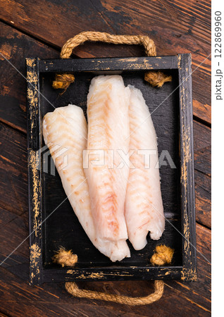 Fresh fish meat, Raw cod loin pieces without skin in wooden tray. wooden background. top view Fresh fish meat, Raw cod loin pieces without skin in wooden tray. wooden background. top view 122869960