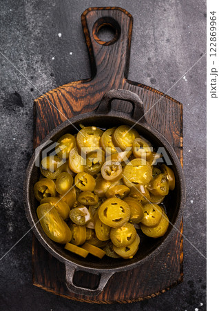 Pickled Jalapeno, Marinated Green Mexican pepper Slices in a skillet. black background. top view Pickled Jalapeno, Marinated Green Mexican pepper Slices in a skillet. black background. top view 122869964
