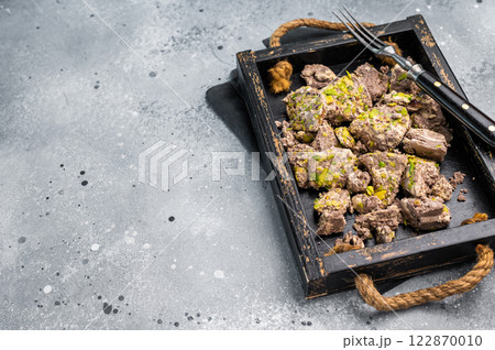Turkish Halva with pistachio and Sesame in a wooden tray. Natural vegetarian sweets. gray background. top view Turkish Halva with pistachio and Sesame in a wooden tray. Natural vegetarian sweets. gray background. top view 122870010