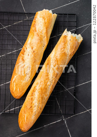 French bread baguette on a steel rack. black background. top view French bread baguette on a steel rack. black background. top view 122870042