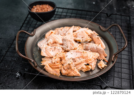 Roast salmon fillet, pulled fish meat on a steel tray. black background. Top view 122870124