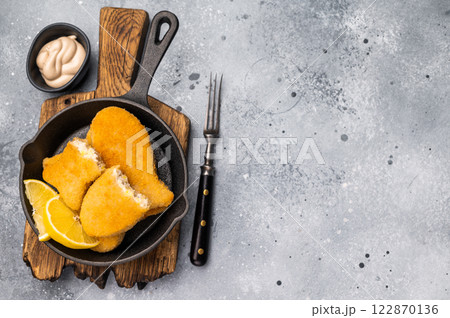 Breaded gold Fish sticks in pan. grey background. top view 122870136