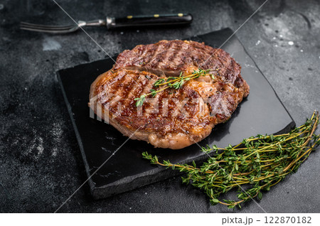 Rib eye steak with herbs on marble board, grilled prime beef meat. black background. top view 122870182