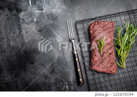 Grilled Flank steak, beef meat on rack with rosemary. black background. top view 122870194