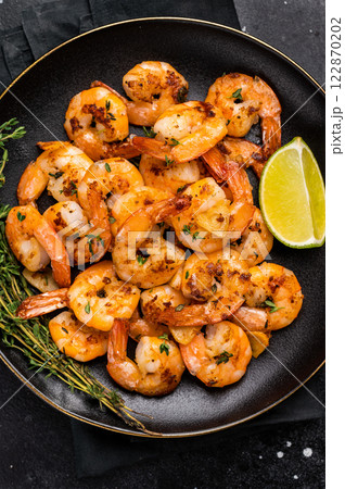 Grilled spicy Shrimps Prawns with garlic and lime in a plate. Black background. Top view 122870202