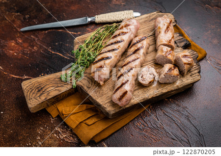 Fried on BBQ beef and pork sausages on wooden cutting board. brown background. top view Fried on BBQ beef and pork sausages on wooden cutting board. brown background. top view 122870205