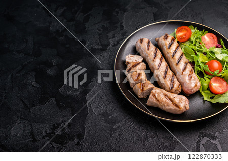 Salad with grilled beef and pork sausages on plate. black background. top view 122870333