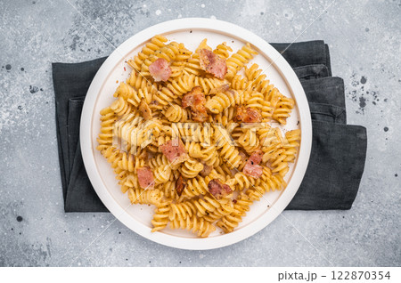 Carbonara pasta topped with crispy bacon bits and parmesan cheese in a plate. Gray background. Top view Carbonara pasta topped with crispy bacon bits and parmesan cheese in a plate. Gray background. Top view 122870354
