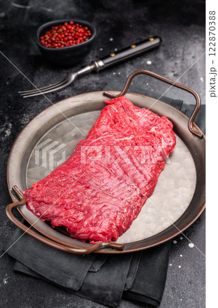 Uncooked flank steak, raw beef flap meat steak. black background. top view Uncooked flank steak, raw beef flap meat steak. black background. top view 122870388