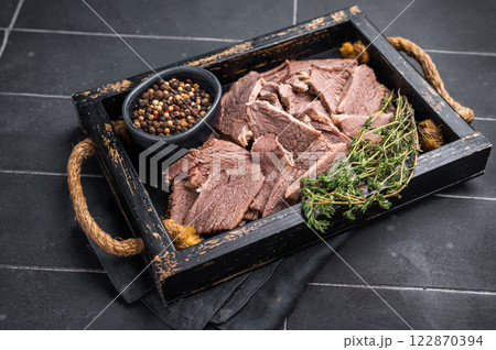Cooked boiled sliced beef meat in wooden tray. black background. top view Cooked boiled sliced beef meat in wooden tray. black background. top view 122870394
