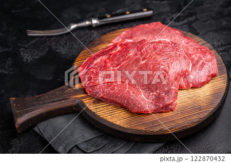 Butcher board with raw beef cheeks, uncooked meat. black background. top view 122870432