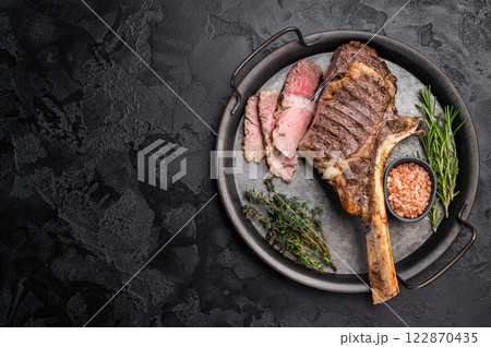 Roasted Tomahawk beef steak, roast dry aged rib eye with bone. black background. top view Roasted Tomahawk beef steak, roast dry aged rib eye with bone. black background. top view 122870435
