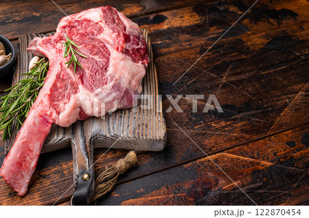 Raw Tomahawk beef steak, fresh black angus ribeye with bone on wooden board. wooden background. top view Raw Tomahawk beef steak, fresh black angus ribeye with bone on wooden board. wooden background. top view 122870454