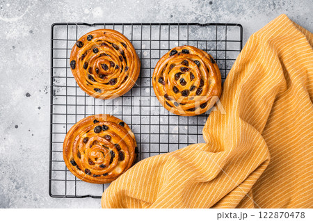Baked Danish pastry, raisin bun on steel rack. grey background. top view Baked Danish pastry, raisin bun on steel rack. grey background. top view 122870478