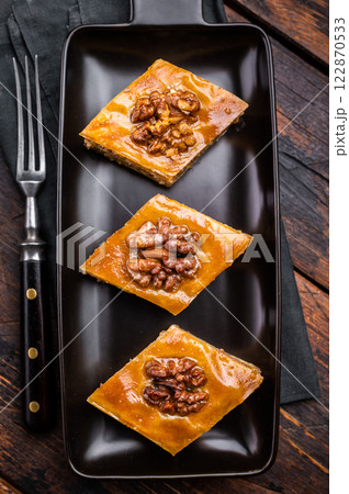 Homemade Walnut Baklava with honey on plate. wooden background. top view Homemade Walnut Baklava with honey on plate. wooden background. top view 122870533