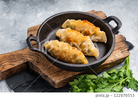 Fried Korean Dumplings with meat and vegetables in skillet. grey background. top view Fried Korean Dumplings with meat and vegetables in skillet. grey background. top view 122870553