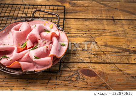 Mortadella sausage slices with pistachios for sandwiches in steel tray. wooden background. top view Mortadella sausage slices with pistachios for sandwiches in steel tray. wooden background. top view 122870619